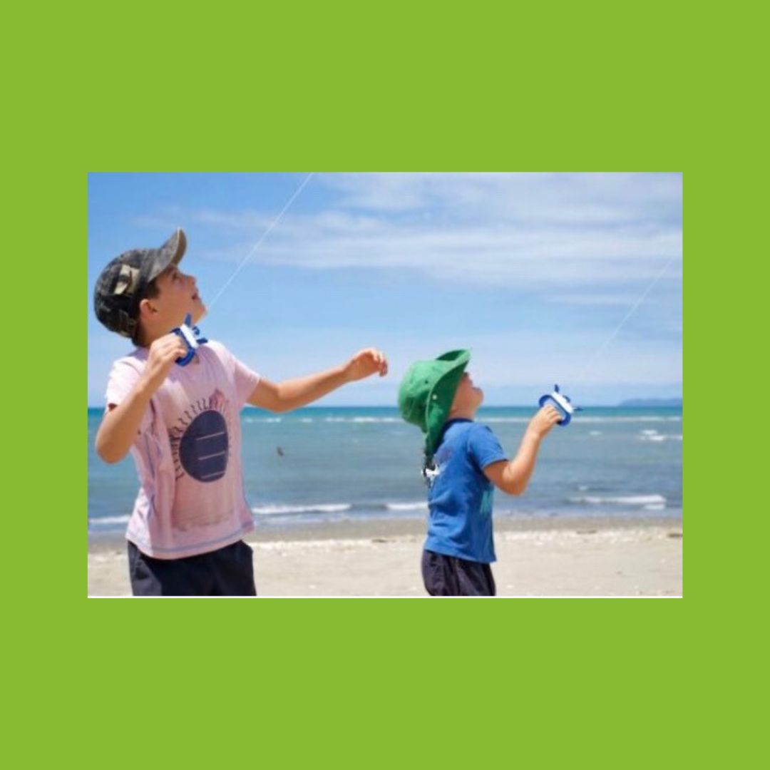 2 children holding string flying their kites